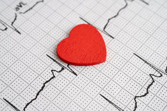 Red fabric heart on top of ECG paper with black lines