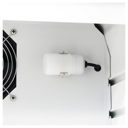 Close-up of a white cylindrical component with a black cable attached, mounted on a white metal surface next to a black fan grille.